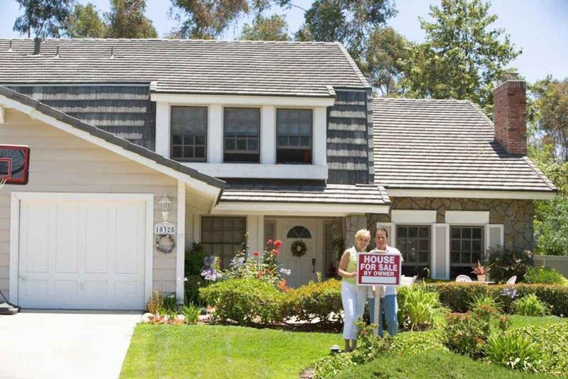 A couple stands in front of their house in Orlando, FL, holding a sign together