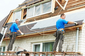 Two men on a roof using a ladder for construction work in Orlando, FL